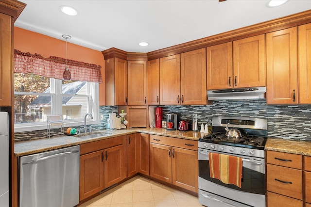 kitchen featuring under cabinet range hood, appliances with stainless steel finishes, brown cabinetry, and a sink