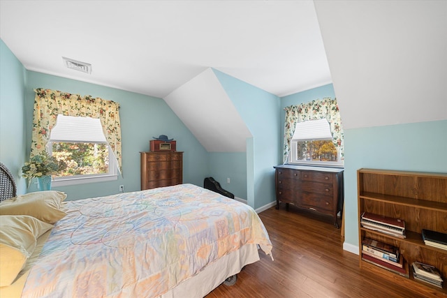 bedroom featuring lofted ceiling, visible vents, baseboards, and wood finished floors