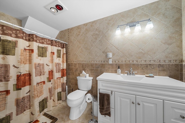 bathroom with toilet, curtained shower, tile patterned flooring, vanity, and tile walls