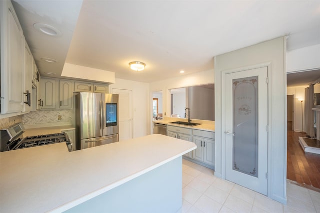 kitchen with kitchen peninsula, decorative backsplash, stainless steel appliances, and sink