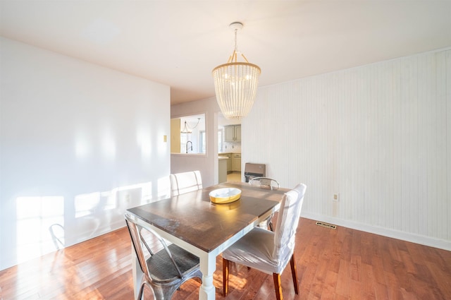 dining room with hardwood / wood-style floors and a notable chandelier