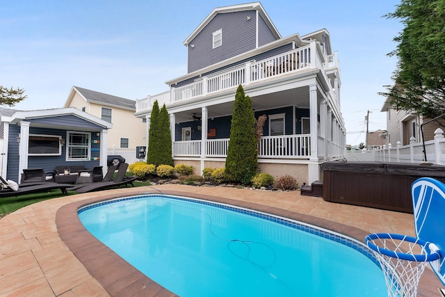 rear view of house featuring a swimming pool with hot tub, a balcony, ceiling fan, and a patio