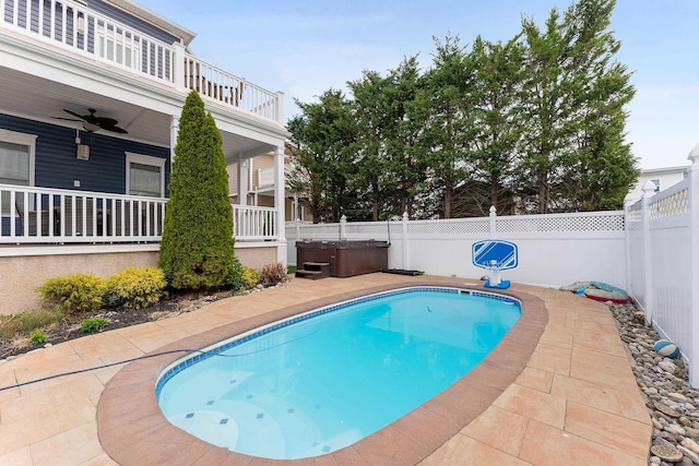 view of swimming pool with ceiling fan, a patio, and a hot tub