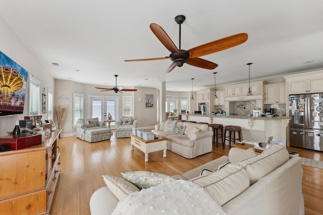 living room with ceiling fan, french doors, and light hardwood / wood-style flooring