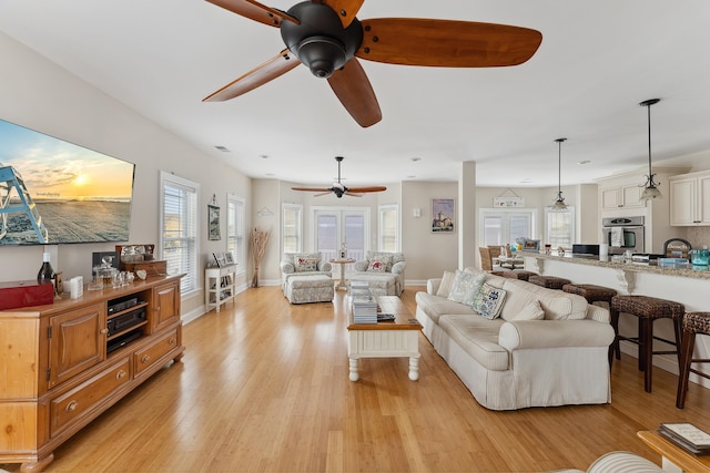 living room featuring ceiling fan, french doors, light hardwood / wood-style floors, and sink