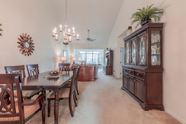 carpeted dining space featuring ceiling fan with notable chandelier and high vaulted ceiling