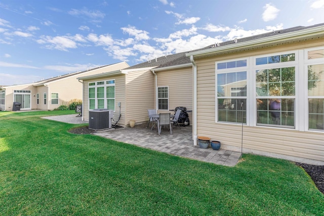 rear view of property featuring cooling unit, a patio area, and a yard