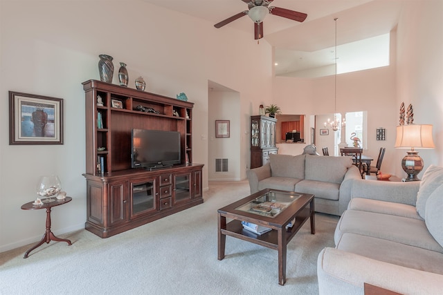 living room featuring ceiling fan with notable chandelier, a towering ceiling, and light carpet