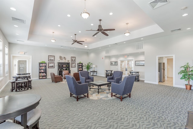 living room featuring a tray ceiling, ceiling fan, light colored carpet, and a high ceiling