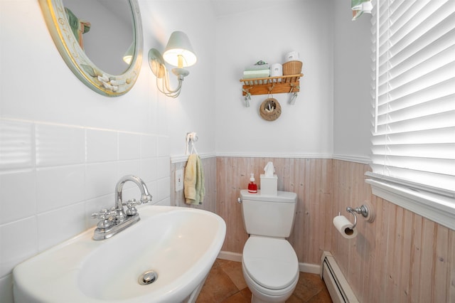 bathroom featuring toilet, tile patterned floors, a baseboard heating unit, and sink