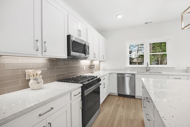 11 Oak Ave, Villas, NJ 08251 - kitchen with stainless steel appliances, light wood-style floors, white cabinets, a sink, and visible vents