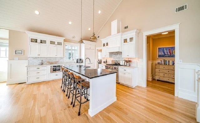 187 104th St, Stone Harbor, NJ 08247 - kitchen with stainless steel range, a breakfast bar area, a wainscoted wall, light wood-type flooring, and plenty of natural light