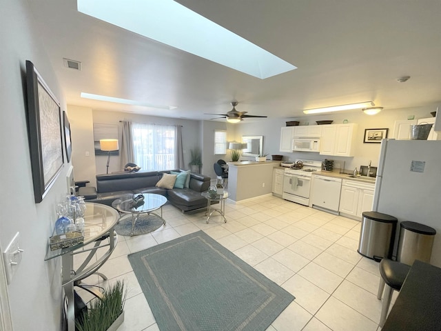 living room featuring a ceiling fan, light tile patterned floors, a skylight, and visible vents