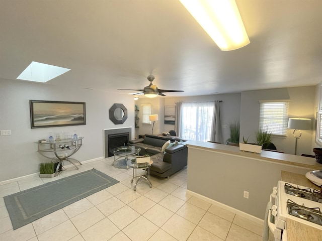 living room featuring light tile patterned floors, a fireplace, and a skylight
