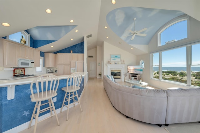 living room featuring ceiling fan, light hardwood / wood-style flooring, and high vaulted ceiling