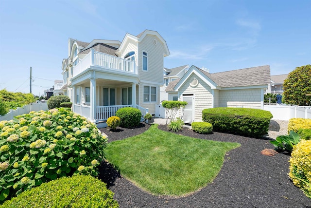 view of front facade featuring a porch, a balcony, and a front lawn