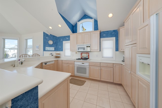 kitchen featuring kitchen peninsula, a wealth of natural light, white appliances, light brown cabinets, and lofted ceiling