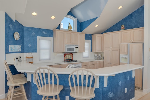 kitchen with kitchen peninsula, paneled fridge, vaulted ceiling, and a breakfast bar area