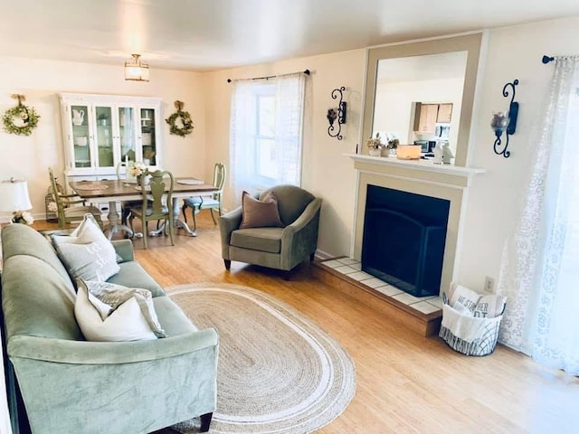 living room with a tile fireplace and wood finished floors