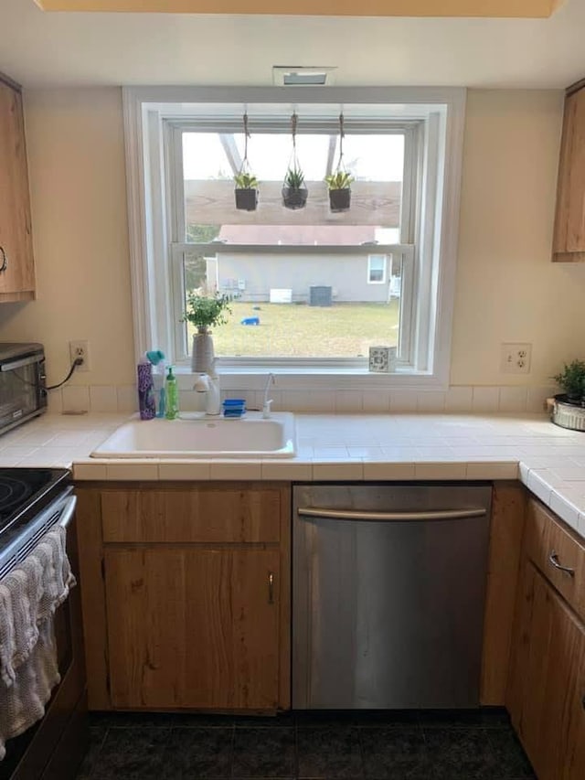 kitchen with tile counters, electric range oven, stainless steel dishwasher, brown cabinetry, and a sink