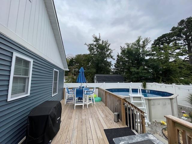 wooden terrace featuring a fenced in pool and grilling area