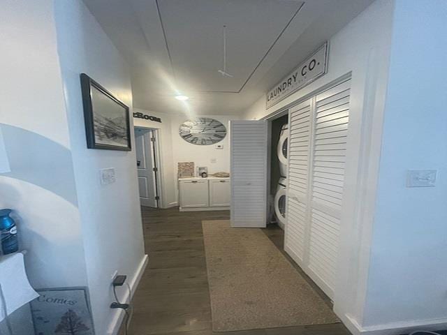 hallway with stacked washer and dryer and dark wood-type flooring