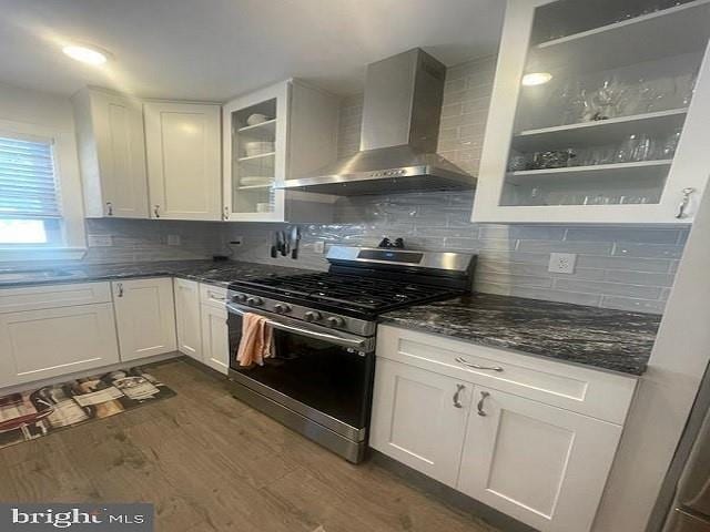 kitchen with white cabinetry, stainless steel range with gas cooktop, dark hardwood / wood-style floors, and wall chimney range hood