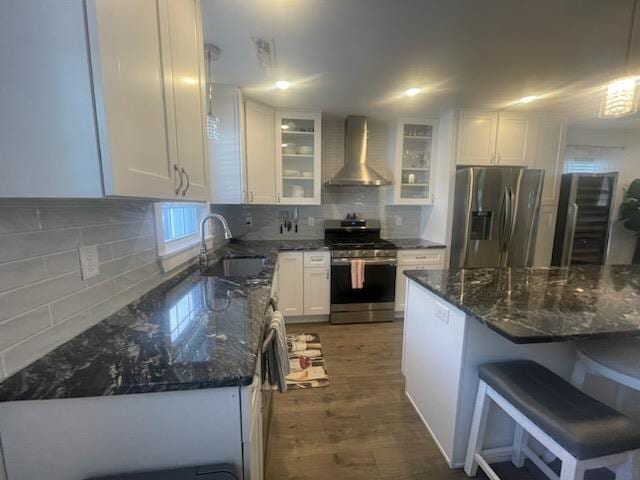 kitchen with backsplash, white cabinets, stainless steel appliances, and wall chimney range hood