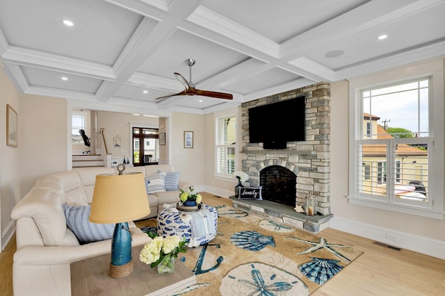 living room with a stone fireplace, beamed ceiling, coffered ceiling, light hardwood / wood-style floors, and crown molding