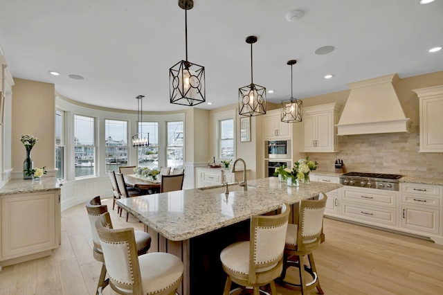 243 N Point Rd, Ocean City, NJ 08226 - kitchen featuring stainless steel gas cooktop, sink, custom exhaust hood, light stone counters, and hanging light fixtures