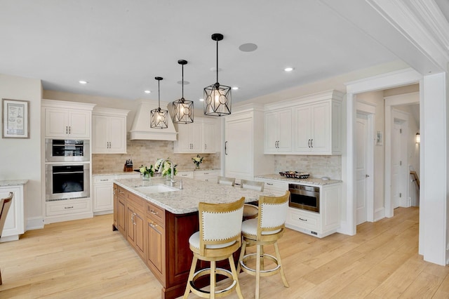243 N Point Rd, Ocean City, NJ 08226 - kitchen featuring sink, white cabinetry, light stone counters, a center island with sink, and pendant lighting