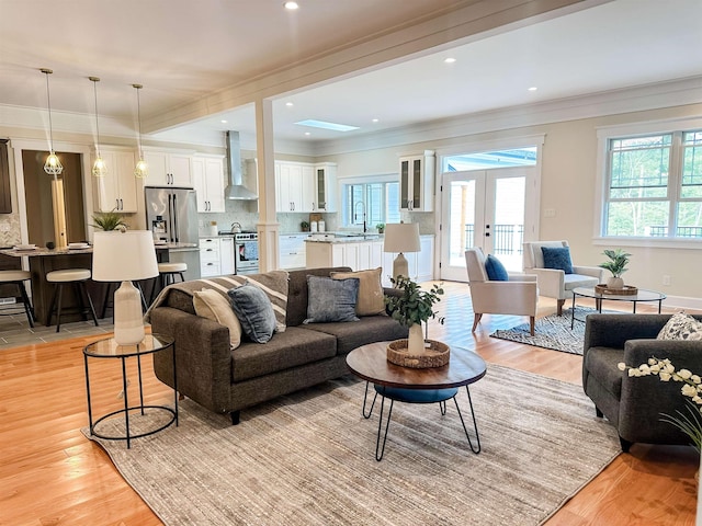 living room featuring light hardwood / wood-style floors, ornamental molding, and sink