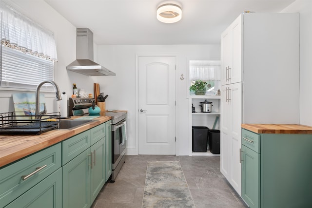 kitchen featuring sink, wall chimney range hood, stainless steel electric range, wooden counters, and white cabinets