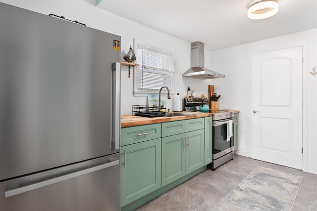 kitchen with butcher block countertops, sink, green cabinetry, stainless steel appliances, and wall chimney exhaust hood