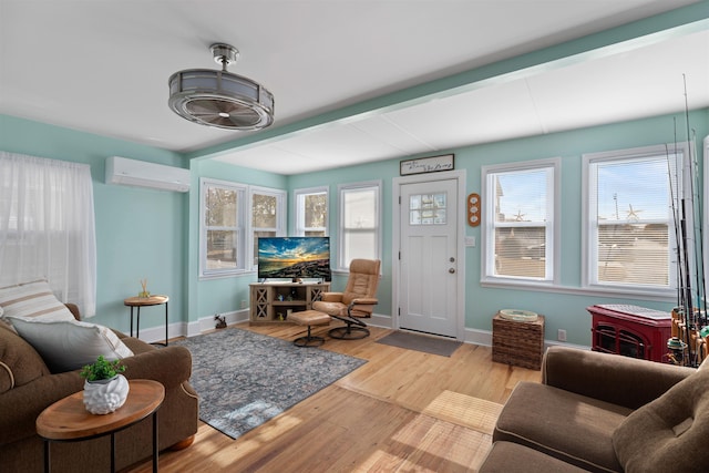 living room with a wall mounted air conditioner, light hardwood / wood-style flooring, and plenty of natural light