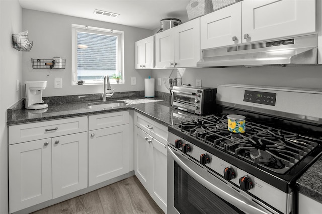 810 E 7th St Unit 4, Ocean City, NJ 08226 - kitchen with stainless steel gas stove, under cabinet range hood, light wood-style flooring, white cabinets, and dark stone counters