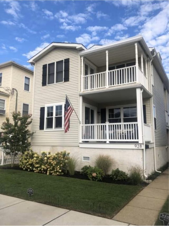 view of front of property featuring a balcony and a front yard