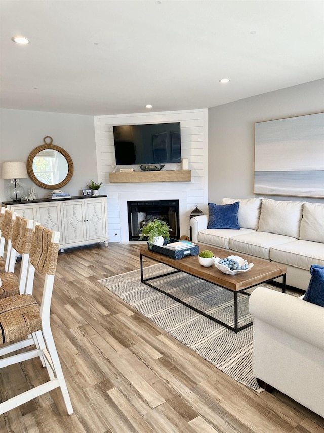 living room with recessed lighting, a large fireplace, and wood finished floors