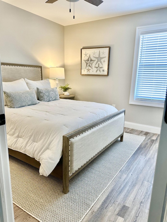 bedroom featuring a ceiling fan, baseboards, and wood finished floors