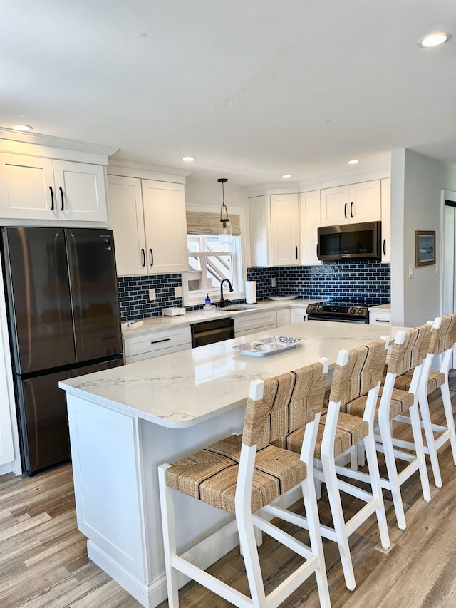 kitchen featuring a sink, appliances with stainless steel finishes, white cabinets, and light wood finished floors