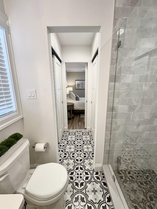 ensuite bathroom with a stall shower, tile patterned floors, toilet, a wealth of natural light, and connected bathroom