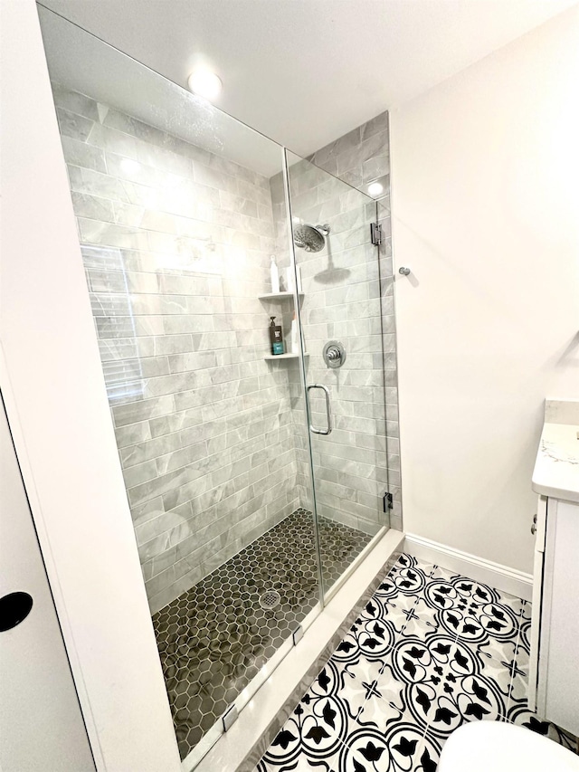 bathroom with vanity, tile patterned floors, baseboards, and a stall shower