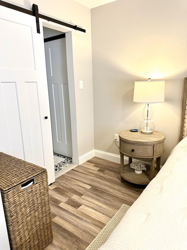 bedroom with baseboards, a barn door, and wood finished floors