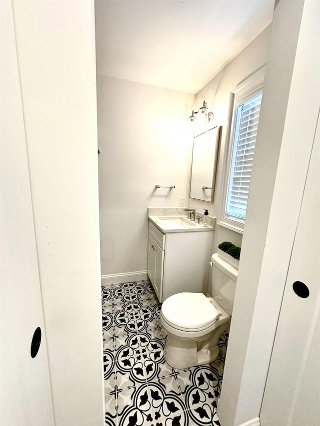 bathroom with tile patterned flooring, toilet, vanity, and baseboards