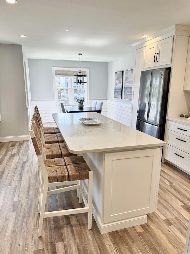 kitchen featuring white cabinets, light wood-type flooring, freestanding refrigerator, and a kitchen island