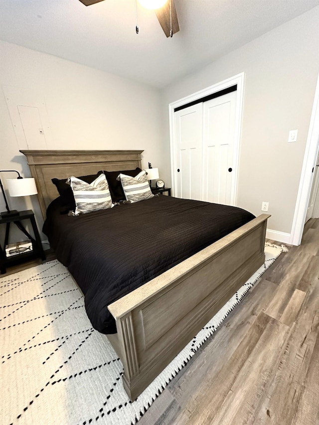 bedroom with a closet, baseboards, wood finished floors, and a ceiling fan