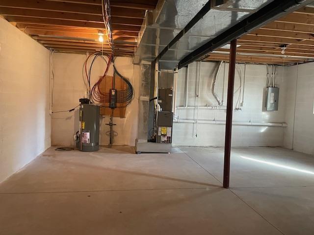 basement featuring heating unit, water heater, and electric panel