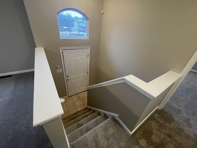 staircase with a towering ceiling and carpet floors