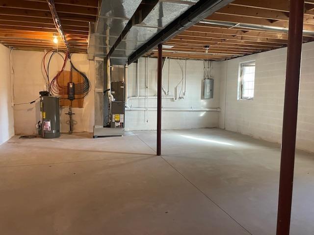 basement with heating unit, electric panel, and water heater