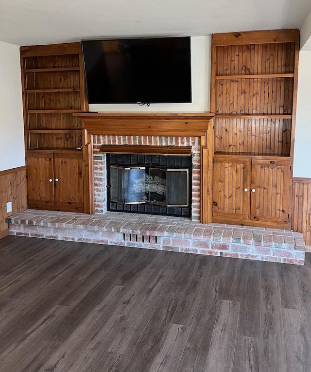 unfurnished living room featuring wood-type flooring, a brick fireplace, and wood walls